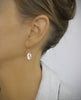 Woman wearing 18K gold plated earrings with Golden Shadow Swarovski crystal drops and balls