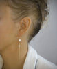 Woman wearing rose freshwater pearl and diamond-cut crystal earrings
