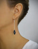 Woman wearing rhodium plated dangle earrings adorned with Black Silver Night Swarovski crystal pavé pendants.