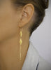 Woman wearing long-length 18K gold plated double flowerlink earrings.
