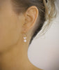 Woman wearing 18K goldplated white pearl earrings with clear Swarovski crystal butterflies