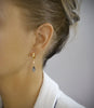 Woman wearing 18K gold plated hoop earrings with "Black Silver Night" Austrian crystal drops.