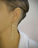 Woman wearing 18K gold plated hoop earrings handmade with Golden Shadow Swarovski crystal drops and seashells.