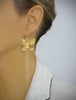 Woman wearing stylish long-length 18K gold plated statement butterfly earrings.