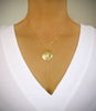 Woman wearing a medium-length 18K gold plated seashell statement Y-necklace
