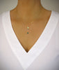 Woman wearing a necklace adorned with a Peridot green crystal butterfly and emerald drop.