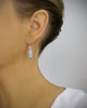 Woman wearing timeless silver earrings adorned with sparkling grey Swarovski crystal pavé pendants.