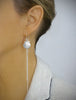 Woman wearing long-length rhodium plated seashell earrings
