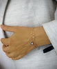 Woman wearing a 18K gold plated double chain flower bracelet decorated with a Tanzanite AB Swarovski crystal drop.