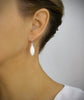 Woman wearing timeless silver earrings adorned with white Swarovski crystal pavé pendants.