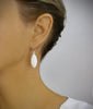 Woman wearing rhodium plated earrings decorated with white Swarovski crystals pavé drops