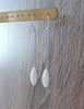 Rhodium plated dangle earrings decorated with sparkling white Swarovski crystal pavé pendants on display.