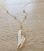 Close-up of a long 18K gold plated necklace with Golden Shadow Swarovski crystal tooth-pendant