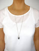 Woman wearing a long silver dragonfly necklace with Black Silver Night Swarovski crystal drop