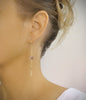 Woman wearing 18K gold plated dangle earrings with "Light Amethyst" Swarovski crystal balls