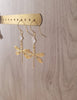  18K gold plated dragonfly and diamond-cut clear crystal earrings on jewellery display.
