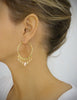 Woman wearing 18K gold plated hoop earrings with Golden Shadow Swarovski crystals