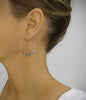 Womann wearing18K gold plated hoop earrings featuring Black Silver Night Swarovski crystals.
