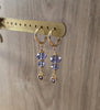 18K goldplated hoop earrings featuring Tanzanite heart and Swarovski crystals on display