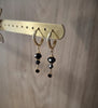 18K gold plated huggie earrings with black Swarovski crystals on display
