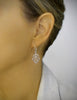 Woman wearing rhodium plated heart filigree earrings with Blue Shade Swarovski crystals