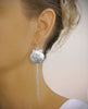 Woman wearing long-length rhodium plated seashell earrings