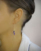 Woman wearing 18K gold plated threader chain earrings handmade with sparkling Tanzanite Swarovski crystal drops.