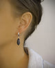Woman wearing silver plated hoop earrings adorned with "Black Silver Night" Swarovski crystal pavé pendants.