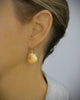 Woman wearing 18K gold plated seashell earrings decorated with crystal charms.