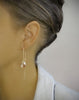 Woman wearing 18K gold plated chain threader earrings decorated with sparkling "Golden Shadow" Swarovski crystal drops.