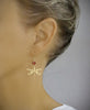 Woman wearing 18K gold plated dragonfly earrings decorated with sparkling "Scarlet Red" Swarovski crystals.