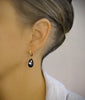 Woman wearing 18K gold plated hoop earrings with "Black Silver Night" Swarovski crystal drops.