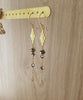Long-length 18K gold plated flowerlink earrings decorated with Black Silver Night Swarovski crystals on display.