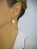 Woman wearing long-length 18K gold plated seashell dangle earrings.