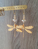 Long-length 18K gold plated dragonfly statement earrings featuring Golden Shadow Swarovski crystals on display.