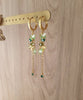 18K gold plated hoop earrings with Peridot green butterflies, Emerald charms and clovers, displayed on jewellery stand.