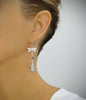 Woman wearing rhodium plated dragonfly earrings adorned with grey Swarovski® crystal pavé drops.