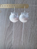 Long-length rhodium plated seashell statement earrings on jewellery display