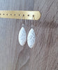 Rhodium plated earrings decorated with white Swarovski crystals pavé drops on display.