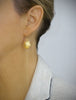 Woman wearing long-length 18K gold plated seashell earrings
